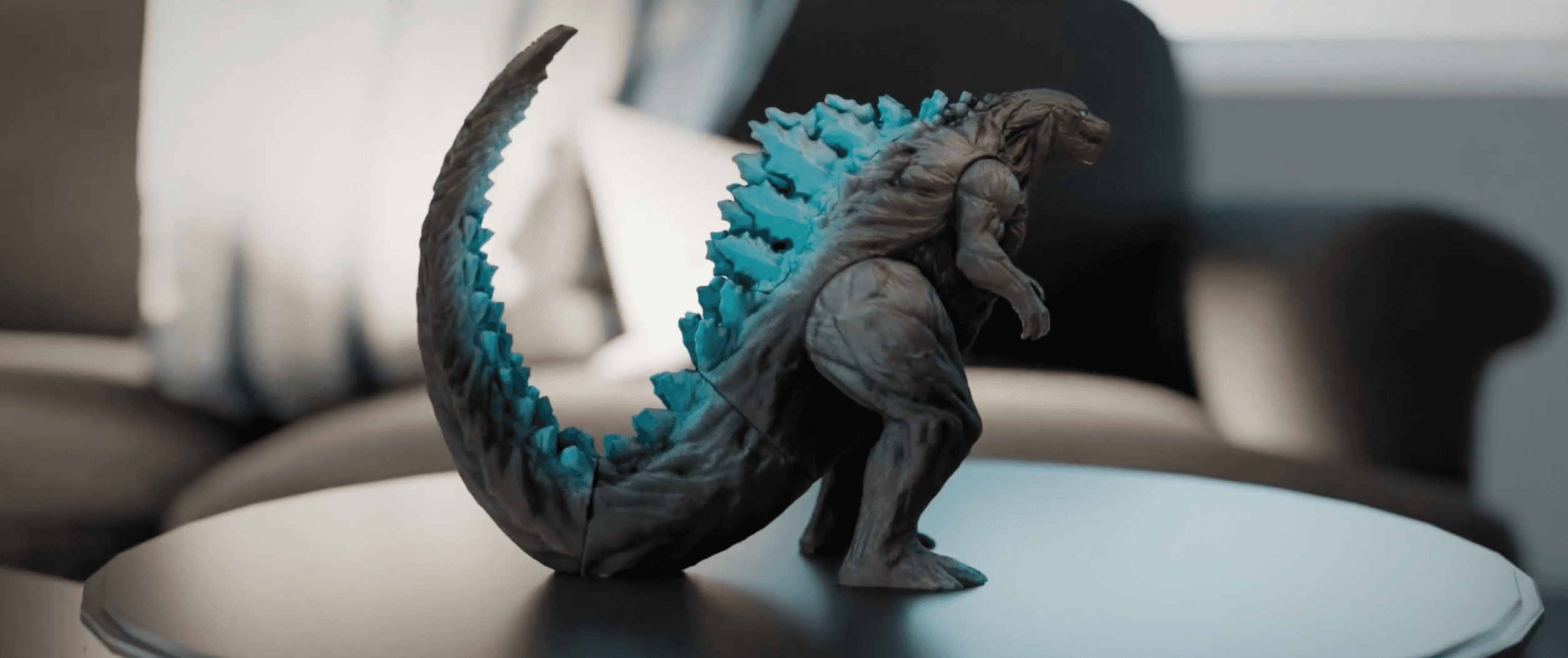 Godzilla action figure placed on a dark round table indoors, showing  a typical static subject setup for 3D Gaussian Splatting capture with  KIRI Engine